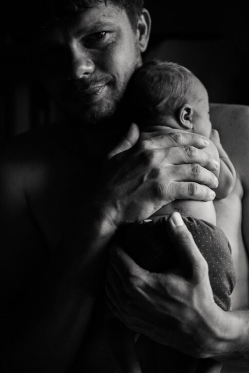 Vater mit Neugeborenen auf Arm nach Hausgeburt , dokumentiert von Der Geburtsfotografin Lisa von Rekowski