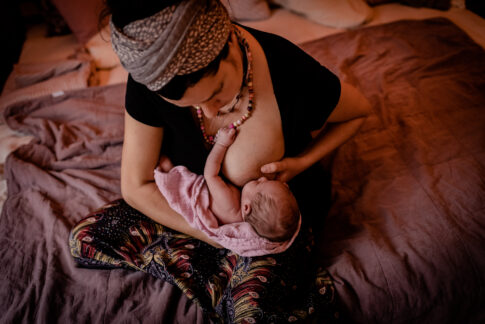 Mutter stillt ihr Neugeborenes Wochenbettshooting von Lisa von Rekowski Geburtsräume Kragen Wiebke Niemann Doula
