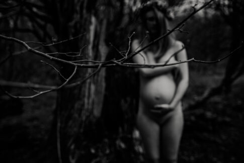 schwarzweißes Ganzkörperporträt verschwommen von einer Mutter beim Babybauchshooting im Wald