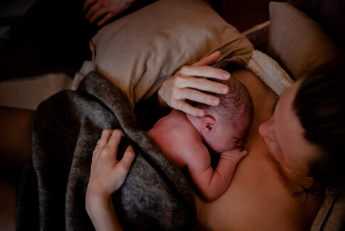 Neugeborenes auf der Brust der Mutter nach der Geburt.. Geburtsfotografie