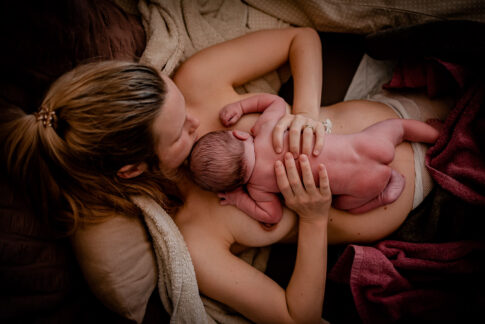 Neugeborenes liegt nach der Geburt nackt auf bauch der Mutter. Geburtsfotografie Celle