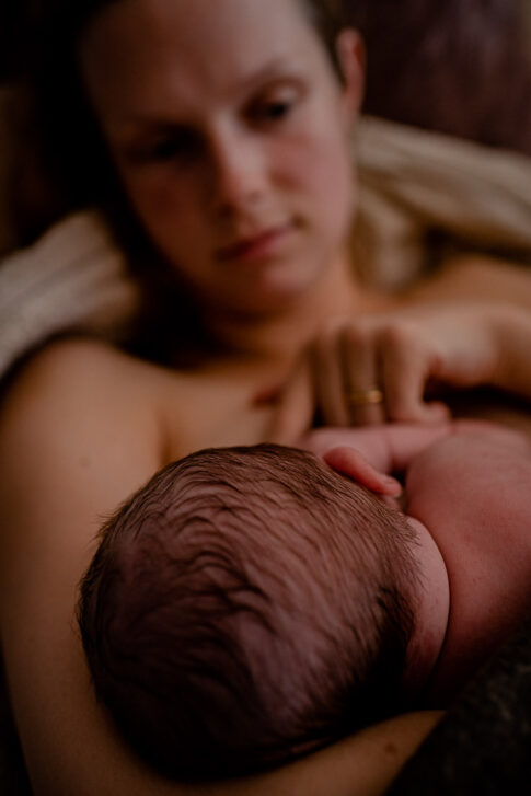 Mutter hilft Baby beim ersten Andocken nach der Geburt