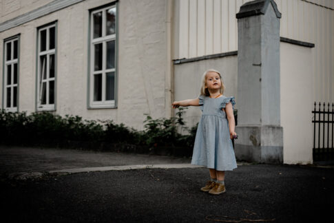 Mädchen steht vor Toreinfahrt und zeigt bestimmt in diese Richtung bei Familienshooting in Celle
