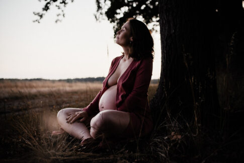 schwangere meditiert vor Baum auf Wiese bei Wolfsburg