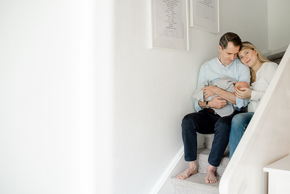 Eltern mit Neugeborenen auf Treppe bei Newbornshooting in Celle, Hannover