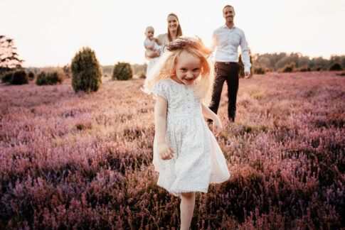 kleines Mädchen rennt vor Eltern auf die Kamera zu bei Familienshooting in der Misselhorner Heide