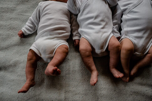 Man sieht nur die Beine von Drillingsbabys auf Decke liegend bei Newbornshooting