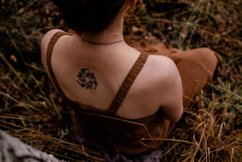 Bild von Rücken mit Tattoo in der Natur bei Schwangerschaftsshooting in Celle