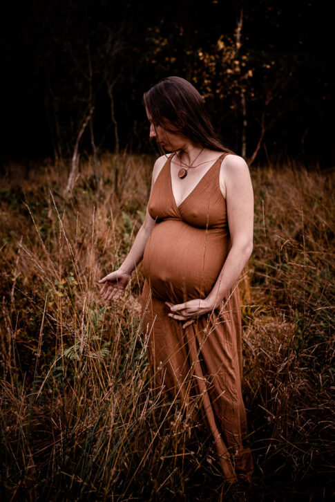 Schwangere Frau wandelt über Wiese im Herbst bei Babybauchshooting Hannover