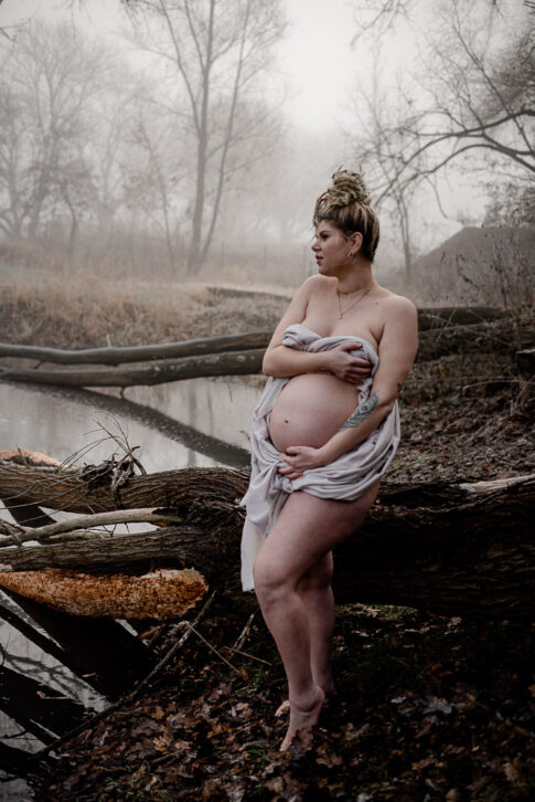 schwangere Frau bei Babybauchfotografie in Hannover am Wasser. Mystische Stimmung durch Nebel.