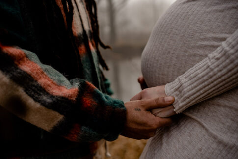 Mann hält die Hand seiner schwangeren Frau im Detail bei Babybauchshooting bei Hannover