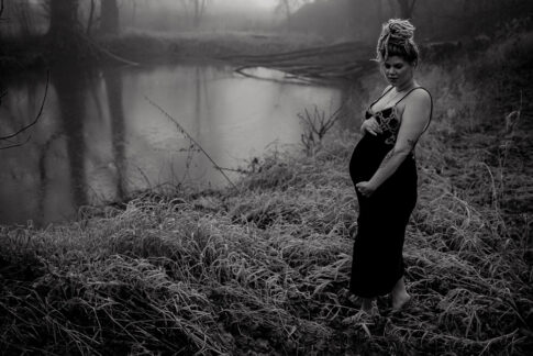 Schwangere Frau in schwarzweiß vor Teich im Nebel