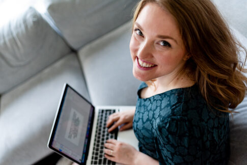 Frau am Laptop lächelt nach oben Richtung Kamera. Businessfotografie Celle, Hannover, Braunschweig