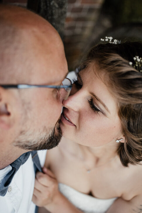 zärtlicher Kuss des Brautpaares wähernd der Hochzeitsfotos in Celle