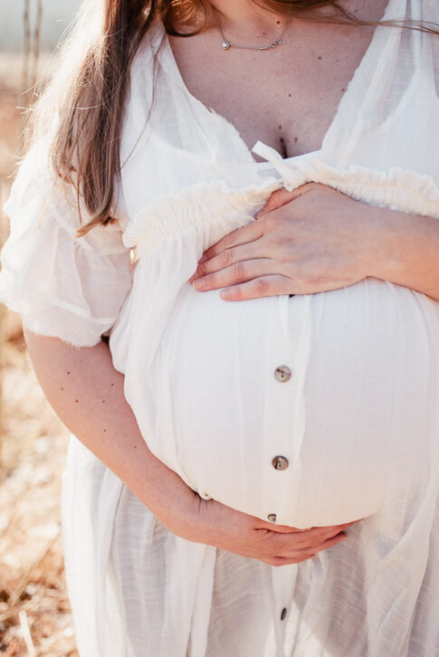 Schwangere Frau in weißem Leinenkleid bei Babybauchshooting bei Hannover