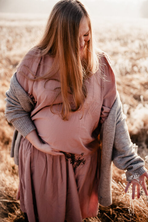 schwangere Frau geht durchs Feld